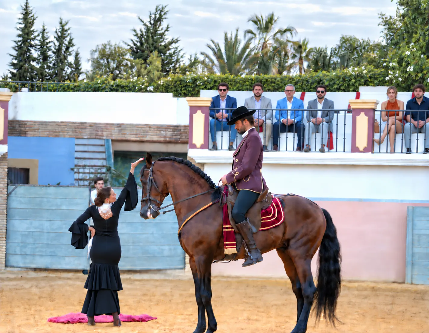 Espetáculo equestre num picadeiro, com um cavaleiro de traje curto e uma bailaora de flamenco diante das bancadas
